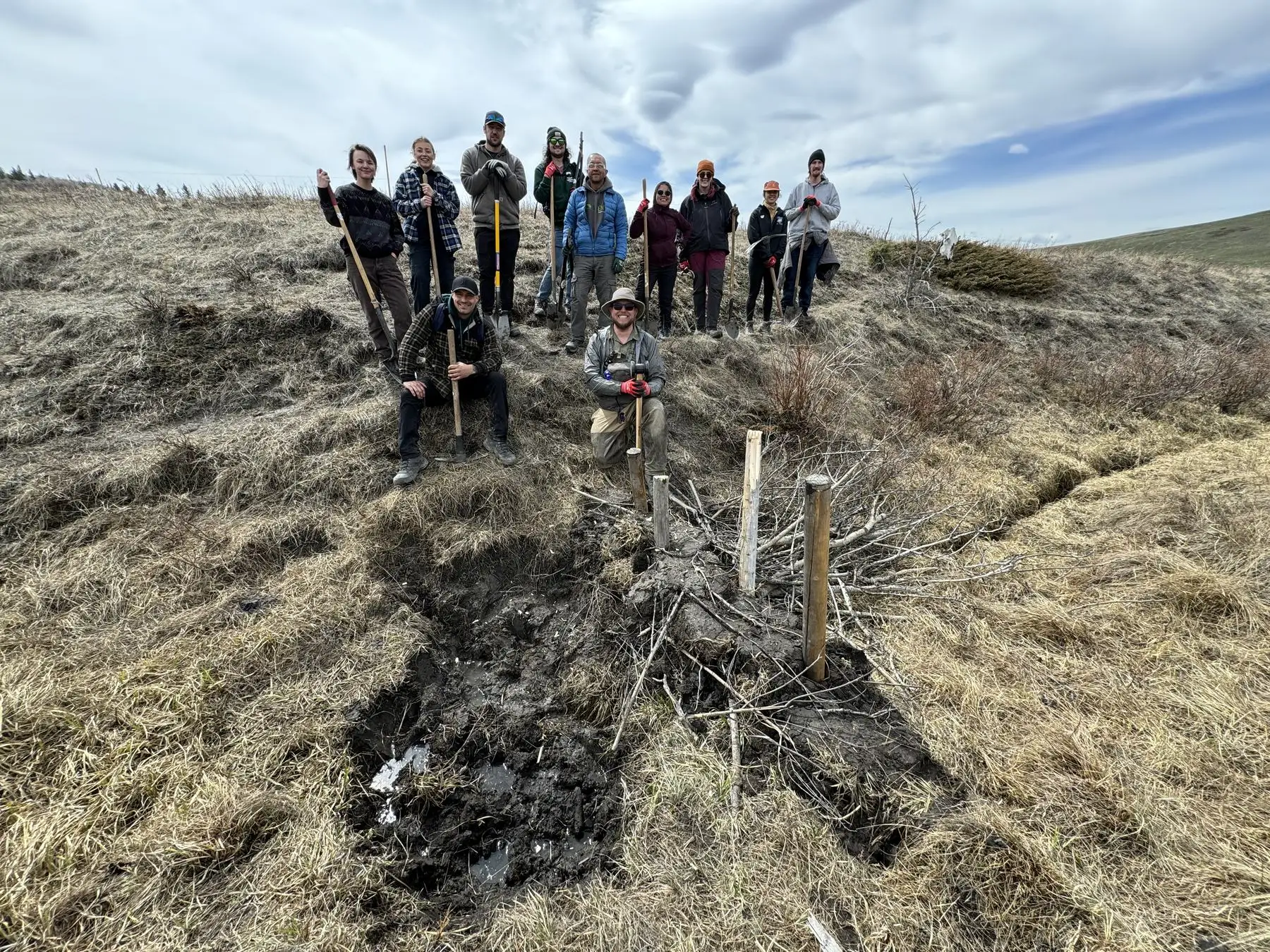A group of students standing on a slope behind a beaver dam analogue